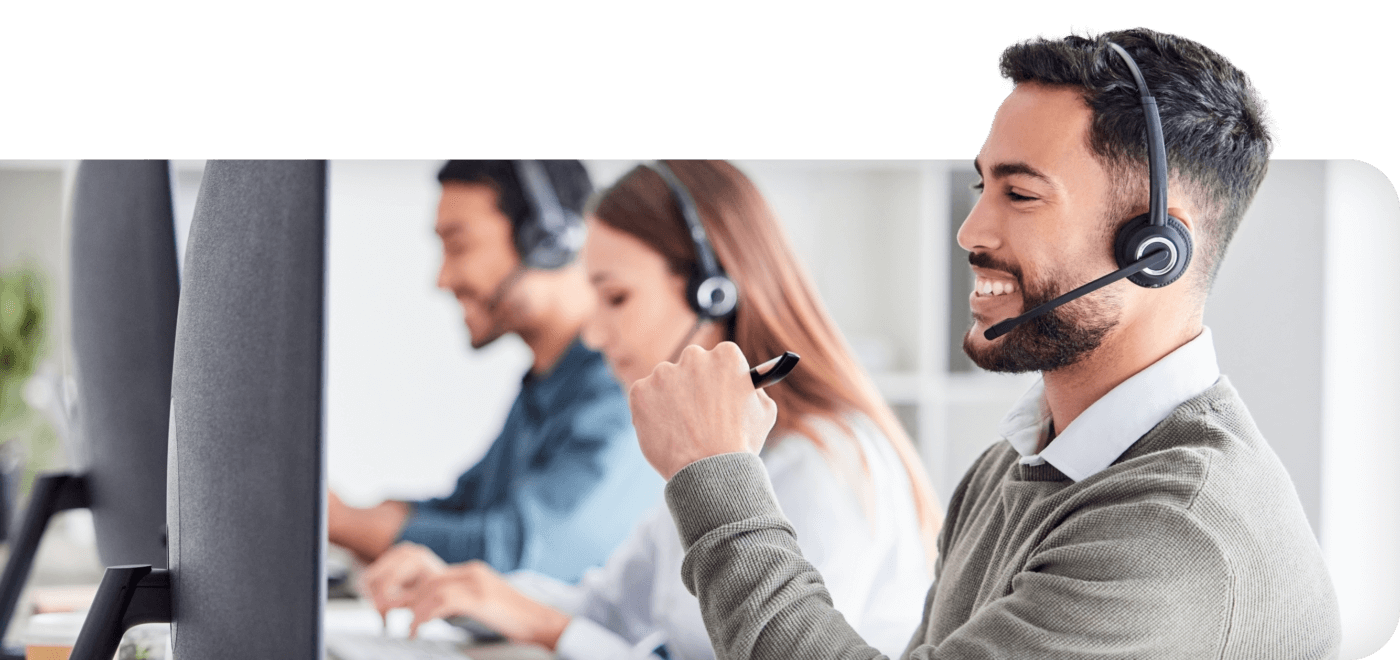Male contact center employee wearing headset looking at computer sharing about AI solutions for the Contact Center