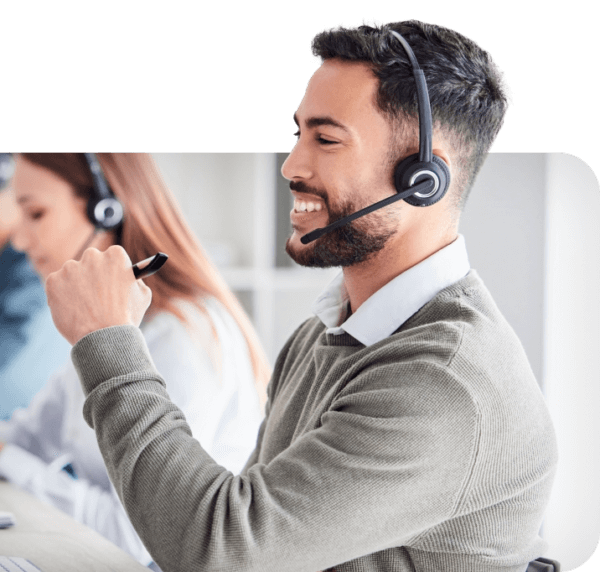 Male contact center employee wearing headset looking at computer sharing about AI solutions for the Contact Center