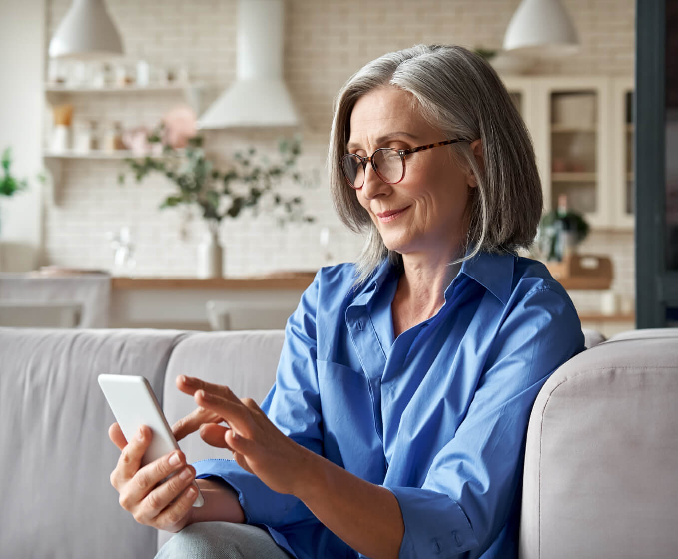 Older woman sitting on a couch looking at her cell phone