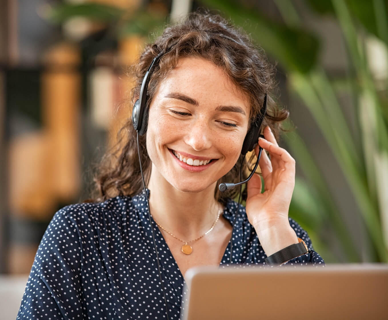 Customer support woman smiling at laptop while on a call on her headset