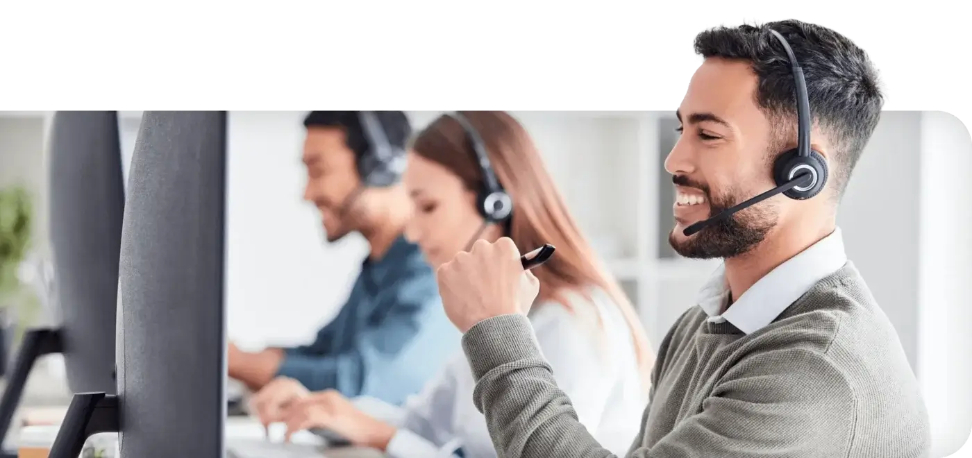 Male contact center employee wearing headset looking at computer sharing about AI solutions for the Contact Center