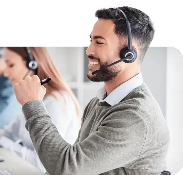 Male contact center employee wearing headset looking at computer sharing about AI solutions for the Contact Center