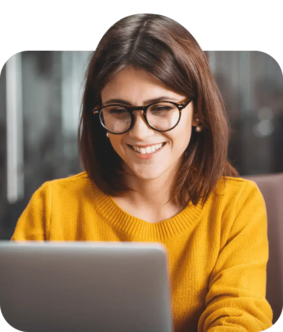 Woman wearing glasses looking at contact center automation solutions on her laptop